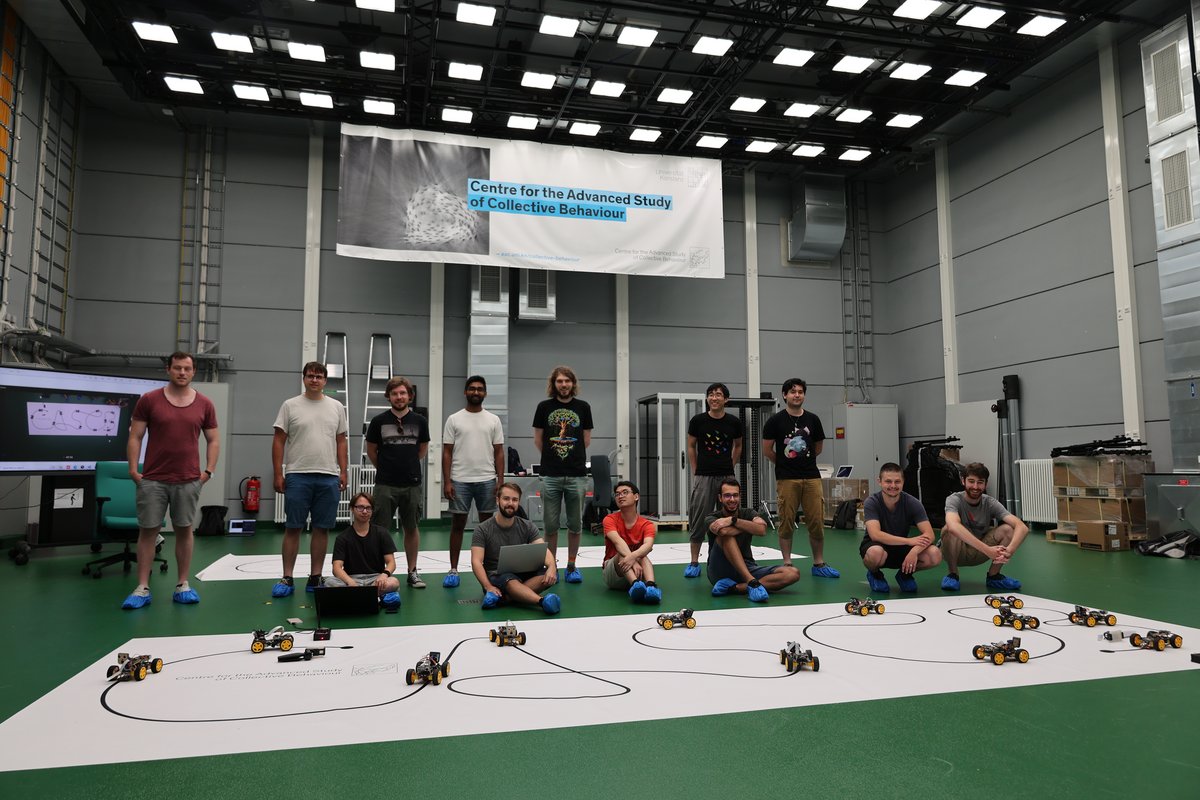 People standing in the Imaging Hangar with robocars on a CASCB banner in the Imaging Hangar 